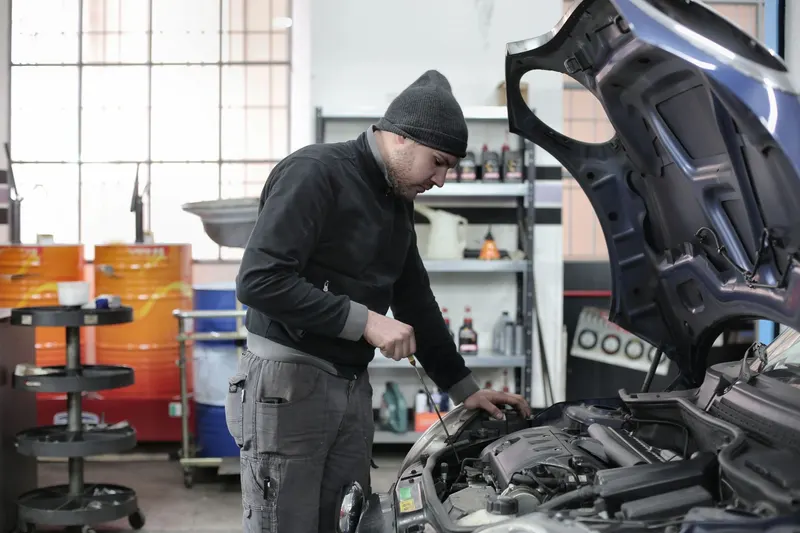 Mechanic checking an engine under an open hood